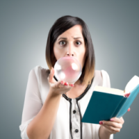 woman blowing a bubble with a book in her hand