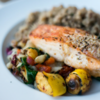 grilled salmon on a bed of roasted vegetables and a side of quinoa