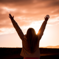 sunrise, woman stretching arms to the sky, radiating joy