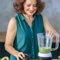 Middle age caucausian woman making smoothie with avocado