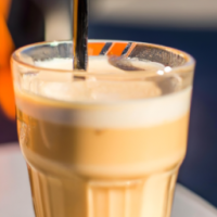 a close up of a vanilla latte in a tall glass wih  a straw