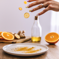 vertical smartphone-style photo of a wooden kitchen counter with simple home remedy ingredients arranged neatly, round white plate in foreground filled with fresh orange slices, a woman’s hand with neat polished nails sprinkling reddish powder over the slices mid-motion, powder particles visible in the air, behind the plate a bottle of apple cider vinegar, a small turmeric spice jar, and a baking soda box, casual kitchen setting, natural indoor lighting, soft shadows, realistic textures, health hack aesthetic, social media wellness post look, slight depth of field blur in background, photorealistic, warm tones --ar 9:16 --v 6 --style raw --quality 2