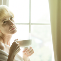 a english women in 50's drinking coffee -looking curious standing in a window with a soft golden light . curtain open to reveal the morning light . . want the theme to be the most powerful part of day 