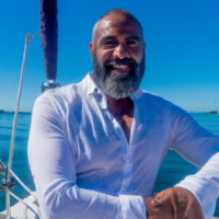 Black Male, 50s, with a beard, on a yacht, facing the camera and smiling