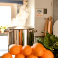 A pot overflowing with boiling oranges in a kitchen with vegetables on the bench