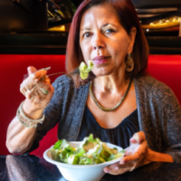 A middle aged latino woman, sitting in a casual restaurant, eating a salad.
