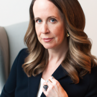 A square portrait professional picture of a 30 year old white female dressed in a business suit.