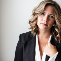 A square portrait professional picture of a 30 year old white female dressed in a business suit.