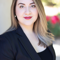 A square portrait professional picture of a 30 year old white female dressed in a business suit.