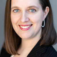 A square portrait professional picture of a 30 year old white female dressed in a business suit.